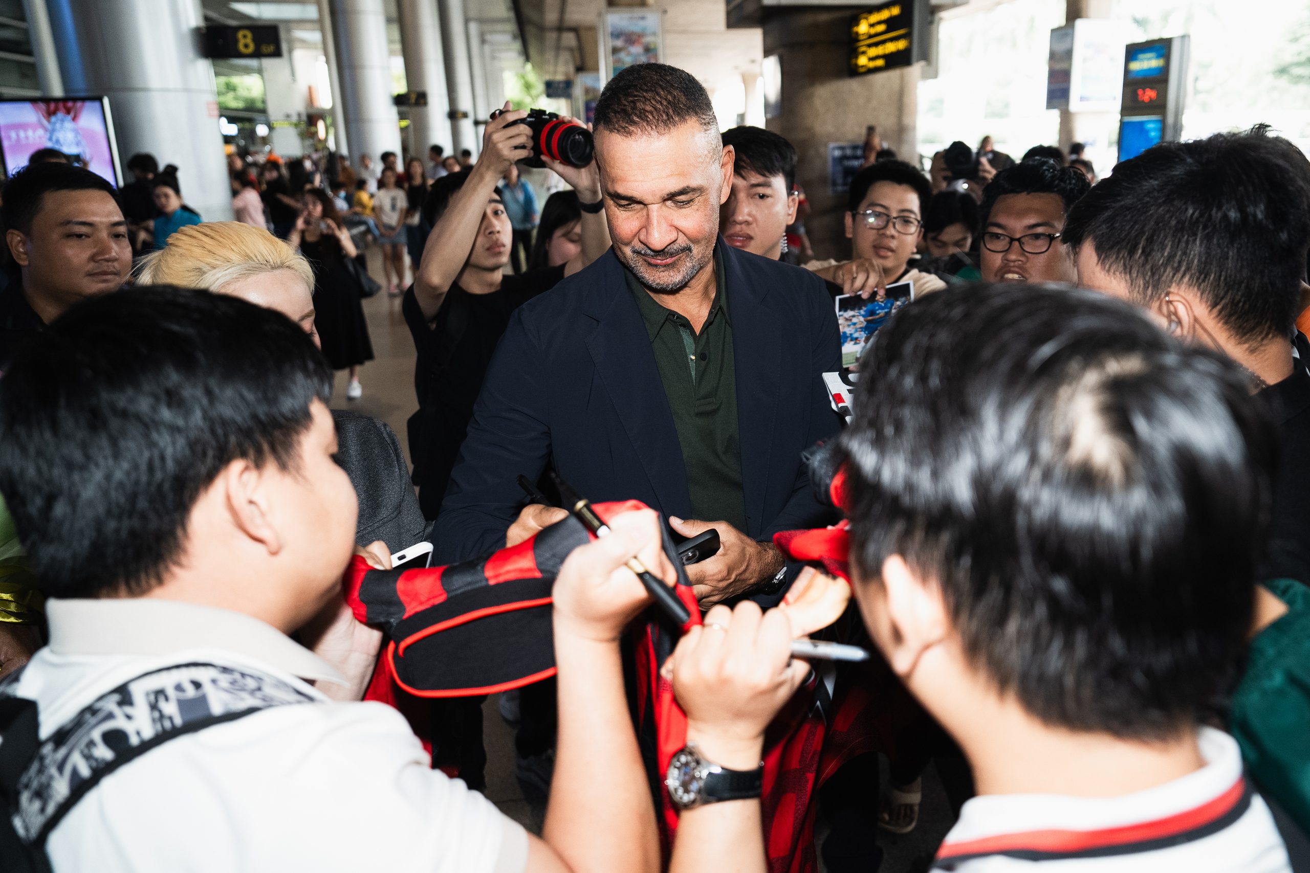 He enthusiastically signs autographs despite just coming off a long flight